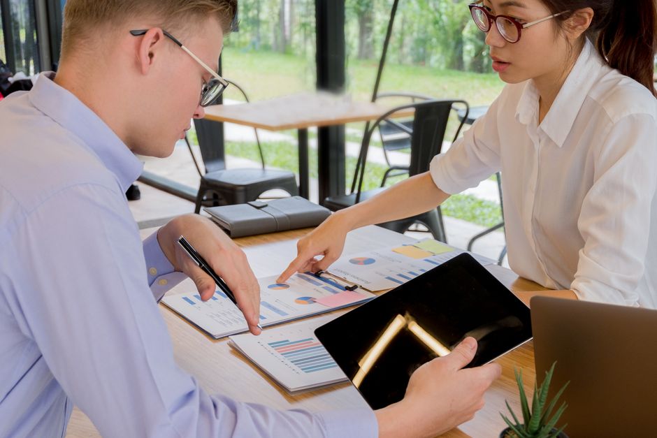 Retenção de Talentos — Team collaboration over financial documents in a modern office setting.